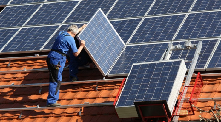 Operario instalando placas solares en el tejado de un edificio | Foto: vía Idealista